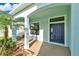 Inviting front porch with a navy blue door, decorative columns, and well-manicured landscaping at 7108 Harvest Glen Ln, Riverview, FL 33578