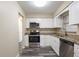 Updated kitchen featuring white cabinets, granite countertops, stainless steel appliances, and gray vinyl flooring at 8528 Gold Ridge Cir, Tampa, FL 33619