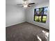 This bedroom features neutral walls, carpet, a ceiling fan, and a bright window with neighborhood views at 36017 Stable Wilk Ave, Zephyrhills, FL 33541