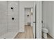 Bright bathroom with tiled walk-in shower, open doorway to walk-in closet, toilet and wood look floors at 10383 Lear St, Spring Hill, FL 34608