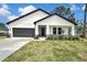 Charming home featuring a modern white exterior, black trim, well-kept lawn, and manicured landscaping at 10383 Lear St, Spring Hill, FL 34608