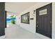 Close-up of the front door, modern mailbox and exterior light fixture on a porch with dark trim at 1154 64Th S Ave, St Petersburg, FL 33705