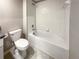 Clean bathroom featuring a tub with white tile surround, a toilet, and a granite countertop at 1526 Cassius St, Lutz, FL 33549