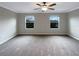 Large main bedroom offering two windows, neutral carpet, and a lighted ceiling fan at 1526 Cassius St, Lutz, FL 33549