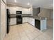 Bright kitchen featuring white cabinets, black appliances, tile floors, and easy access to the staircase at 1526 Cassius St, Lutz, FL 33549