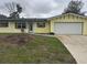 Charming yellow home with a well-manicured lawn and an attached garage, ready for new owners at 1998 Cove Dr, Largo, FL 33774