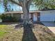 Charming brick home featuring a mature tree, tire swing and a white bicycle at 4706 Lansing Ne St, St Petersburg, FL 33703
