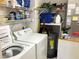 Well-lit laundry room equipped with washer, dryer, shelving, and water heater at 6211 Timber Lake Dr # B4, Sarasota, FL 34243