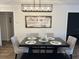 A dining room with a black table and pendant lighting under a sign that says, 