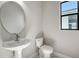 Modern powder room with a pedestal sink, round mirror, and marble flooring at 4541 Mondrian Ct, Sarasota, FL 34240