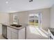 Granite kitchen island with sink and stainless-steel dishwasher, next to sliding glass doors and backyard view at 1317 Arrow St, Port Charlotte, FL 33952