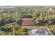 Aerial view of a home with boarded-up windows and a brown roof, surrounded by dense trees at 6098 San Salvador Rd, North Port, FL 34291