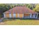 Rear view of a boarded-up, single-story home with a large patio and overgrown lawn surrounded by trees at 6098 San Salvador Rd, North Port, FL 34291