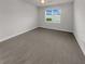 Neutral toned bedroom with carpeted floors, a window, and minimal decor at 9793 Rally Spring Loop, Wesley Chapel, FL 33545