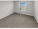 Cozy bedroom with carpet floors and a window overlooking the neighborhood at 9793 Rally Spring Loop, Wesley Chapel, FL 33545