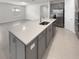 Bright kitchen featuring an island with gray cabinets, stainless steel appliances, and tile floors at 9793 Rally Spring Loop, Wesley Chapel, FL 33545