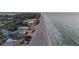 An aerial view features beachfront homes next to a sandy beach with the ocean's waves and city in the background at 2200 Bay Blvd # B, Indian Rocks Beach, FL 33785