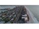 An aerial view features the coast with beachfront homes, a road, and the ocean with a city in the background at 2200 Bay Blvd # B, Indian Rocks Beach, FL 33785