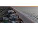 An aerial view features beachfront homes next to a sandy beach with the ocean's waves and city in the background at 2200 Bay Blvd # B, Indian Rocks Beach, FL 33785