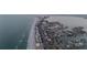 An aerial view features a road alongside the beach, which has the ocean on one side and homes/city on the other at 2200 Bay Blvd # B, Indian Rocks Beach, FL 33785