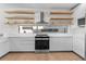 Modern kitchen featuring stainless steel range, wood floating shelves, and light countertops at 2200 Bay Blvd # B, Indian Rocks Beach, FL 33785