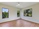 Bedroom featuring wood flooring, a ceiling fan and three windows overlooking landscaping at 82 Venango St, Port Charlotte, FL 33954