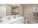 Well-lit bathroom with double sinks, white cabinetry, a large mirror and a separate glass enclosed shower at 22492 Provance Ave, Port Charlotte, FL 33954