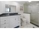 Bathroom with dark granite counters, white cabinets, tiled shower, and glass enclosure at 1000 Cove Cay Dr # 5E, Clearwater, FL 33760