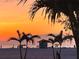 Tranquil beachfront view with silhouetted palms, a lifeguard tower and colorful sunset sky at 1000 Cove Cay Dr # 5E, Clearwater, FL 33760