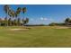 Beautiful golf course view, featuring meticulously maintained greens, a sand trap, and palm trees under a sunny sky at 1000 Cove Cay Dr # 5E, Clearwater, FL 33760