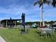 Outdoor seating area with tables, chairs, umbrellas and a vibrant artificial lawn under the open sky at 1000 Cove Cay Dr # 5E, Clearwater, FL 33760