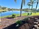 Lush backyard with a tranquil lake view, manicured landscaping, and cozy Adirondack chairs, perfect relaxation at 1727 Waxwing Cir, Venice, FL 34293