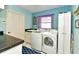 Well-lit laundry room with front-loading machines and granite countertops at 1727 Waxwing Cir, Venice, FL 34293