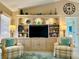 Bright living room with custom built-ins, a large TV, and comfortable armchairs at 1727 Waxwing Cir, Venice, FL 34293