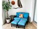 Relaxing patio features a comfy loveseat with floral pillow and dual ottomans, perfect for lounging outdoors at 1727 Waxwing Cir, Venice, FL 34293