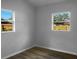 Bright bedroom featuring wood-look floors, neutral walls, and two windows offering ample natural light at 3305 Acapulco Dr, Riverview, FL 33578