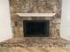 Stone fireplace with a dark opening, light wood mantle, and a raised stone hearth at 3305 Acapulco Dr, Riverview, FL 33578