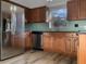 Modern kitchen featuring stainless steel appliances, wood cabinets, and sleek countertops with a green backsplash at 3305 Acapulco Dr, Riverview, FL 33578