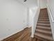 Modern staircase with wood floors, neutral carpet on stairs, and a white door at 6155 Calle Ochoa St, Zephyrhills, FL 33542