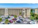 Exterior view of a beige four-story condo building with multiple balconies, lush landscaping, and a full parking lot at 3672 Lake Bayshore Dr # K327, Bradenton, FL 34205