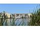 Lakefront condominiums with serene water views framed by tall grasses under a clear blue sky at 3672 Lake Bayshore Dr # K327, Bradenton, FL 34205