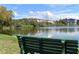 A green bench is placed with a view to see the lake and the condominiums in the background on a bright sunny day at 3672 Lake Bayshore Dr # K327, Bradenton, FL 34205