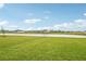 View of the backyard with a large lawn and a pond in the background at 467 Sun Chaser Dr, Nokomis, FL 34275