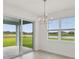 Dining room showcasing a modern chandelier, large windows overlooking a lake, and sliding glass door at 467 Sun Chaser Dr, Nokomis, FL 34275