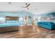 Bright main bedroom with wood-look floors, ceiling fan, and an aqua blue sofa at 1690 Bayshore Dr, Englewood, FL 34223