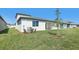 Grassy backyard showcasing an outdoor patio, young tree, and exterior air conditioning unit at 1844 Draughton Dr, Zephyrhills, FL 33541