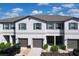 New townhome featuring gray paint, shutters, attached garage, and manicured landscaping at 36495 Garden Wall Way, Zephyrhills, FL 33541