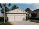 Side view of a single-story home showcasing a spacious two-car garage and well-maintained landscaping at 151 April Rd, Rotonda West, FL 33947