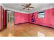 A bedroom with colorful walls, hardwood floors, a ceiling fan, and a large window at 32589 Greenwood Loop, Wesley Chapel, FL 33545