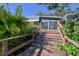 A wooden staircase leads down to a blue house with luscious trees, and a wooden porch at 10952 61St Ave, Seminole, FL 33772
